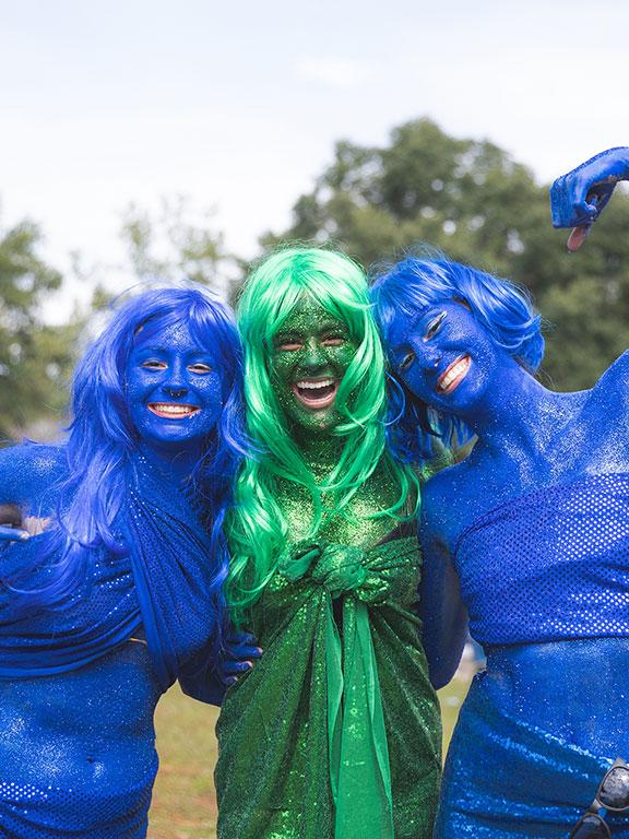 三名UWF学生穿着蓝色和绿色闪闪发光的油漆